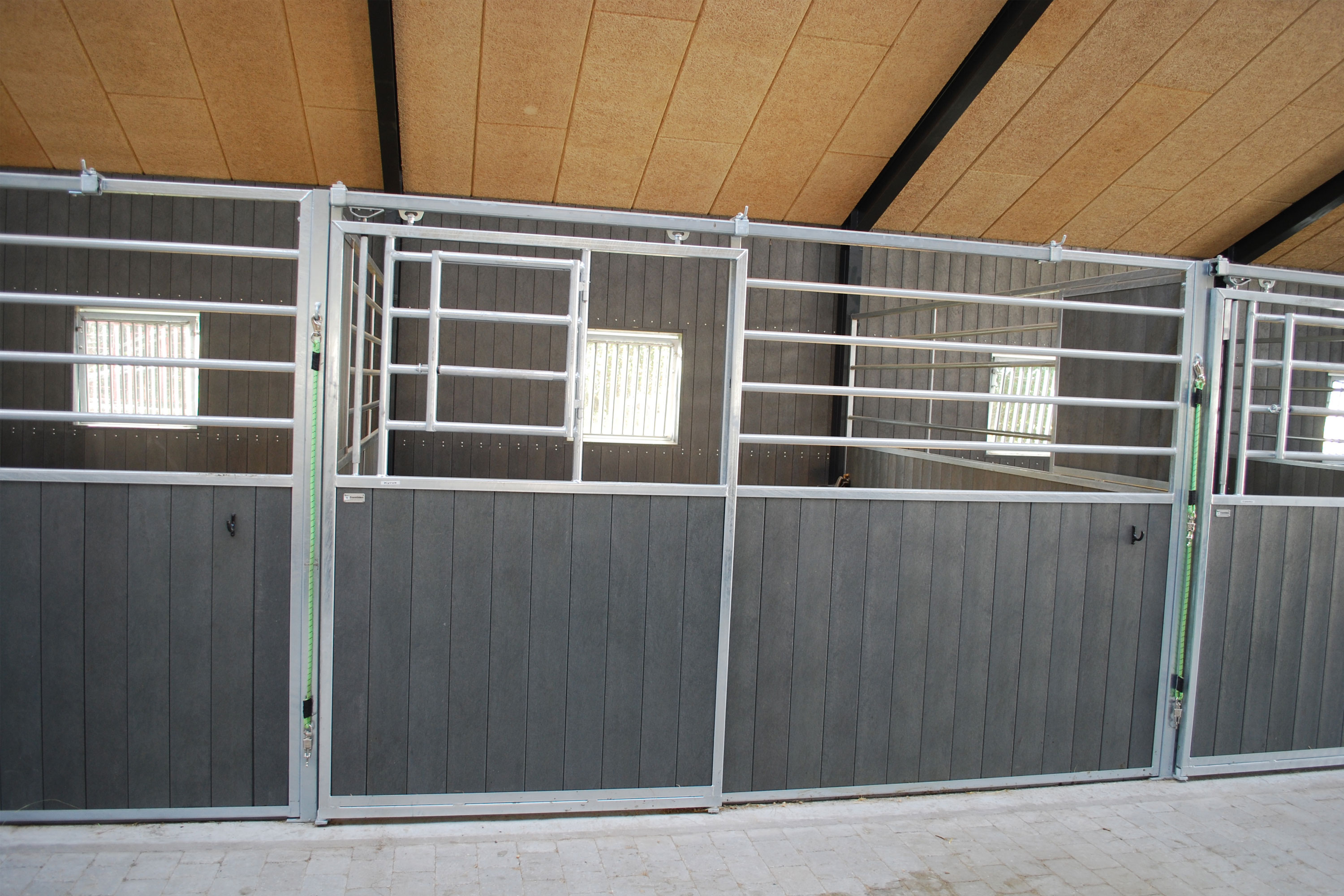 Grand Prix hesteboks med vannrette rør og  lysgrå plastplanker.