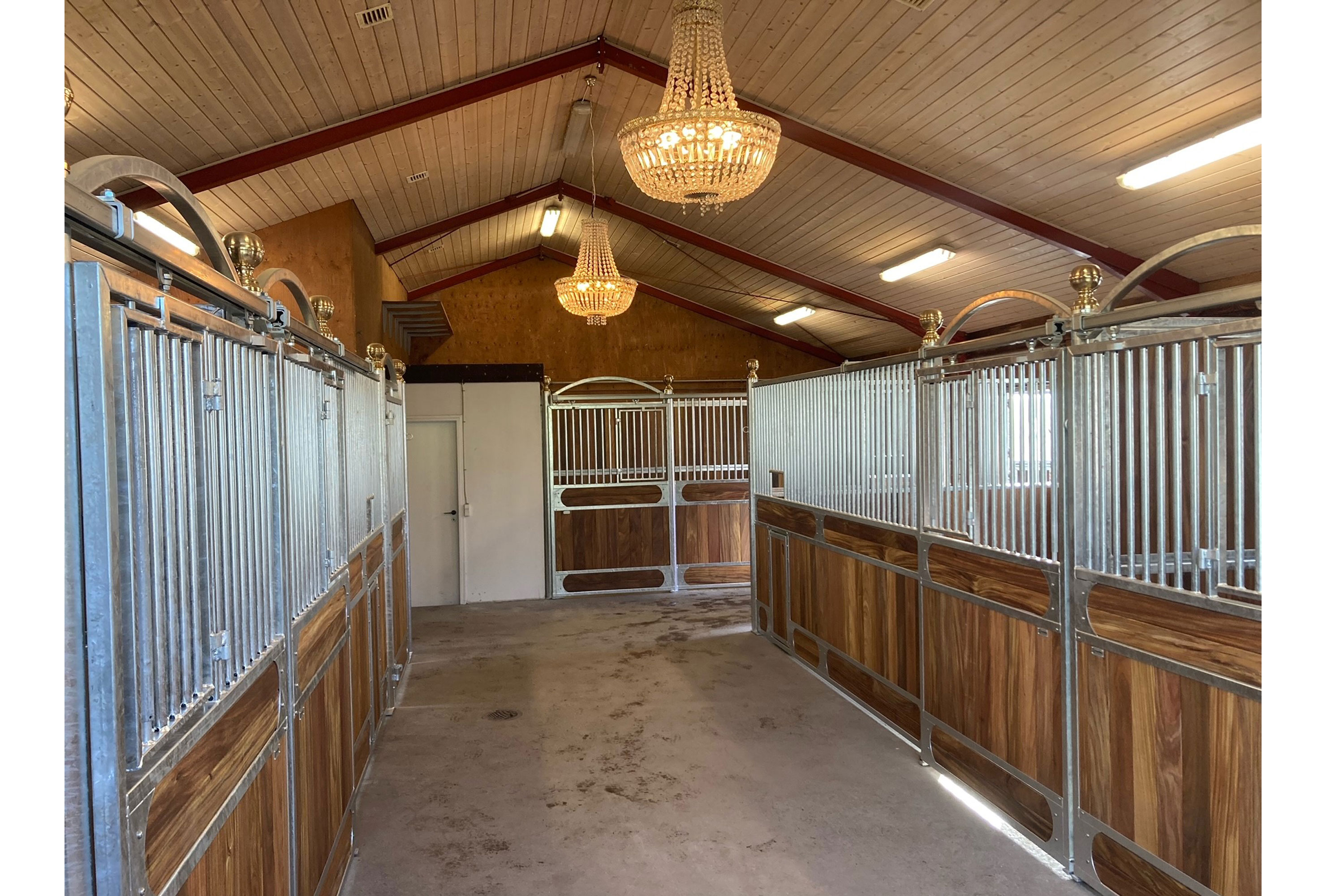 Avantgarde hestebokser med messingkuler og bue over porten.