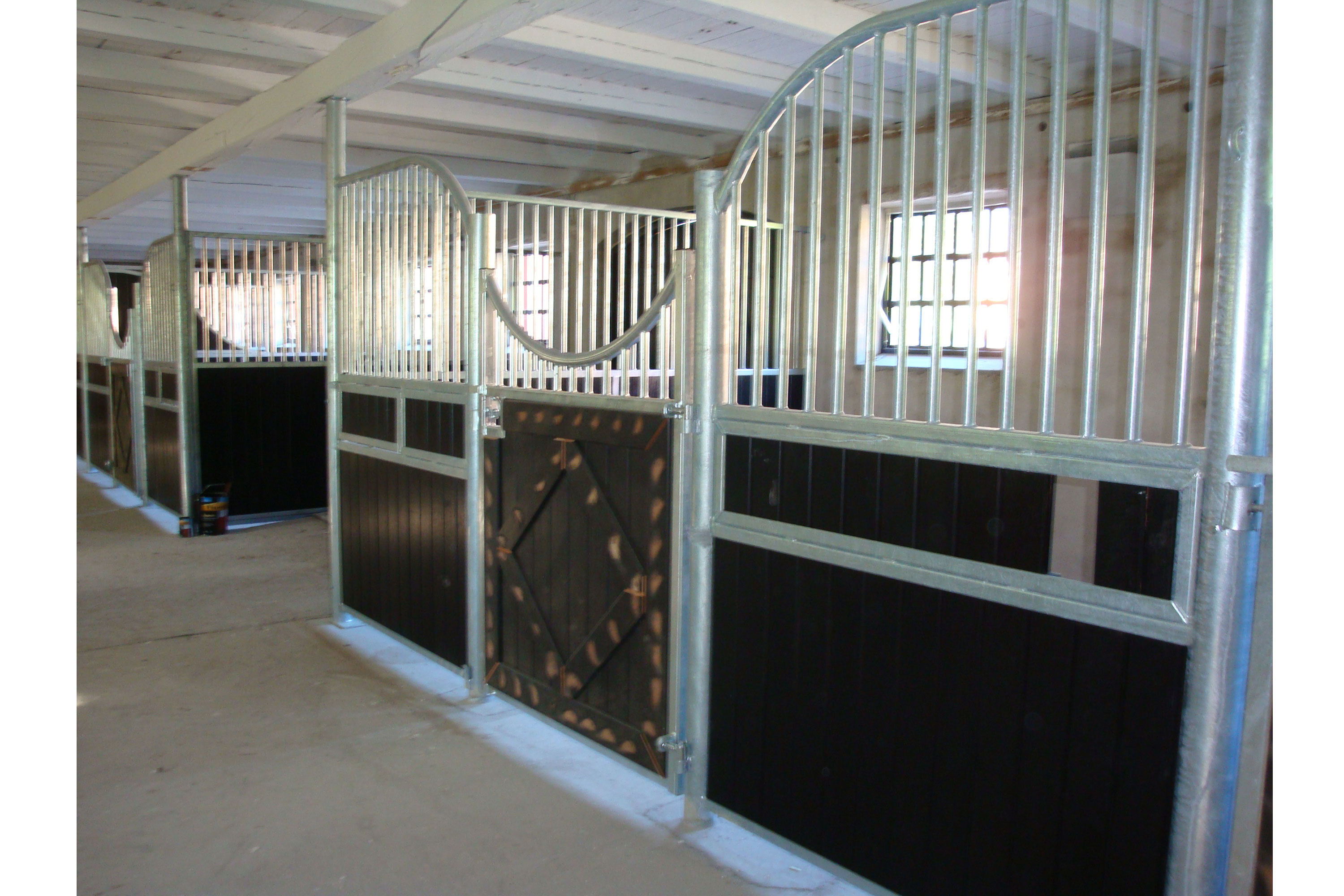 Gulliksen hesteboks med sorte plank og dekorert dør.